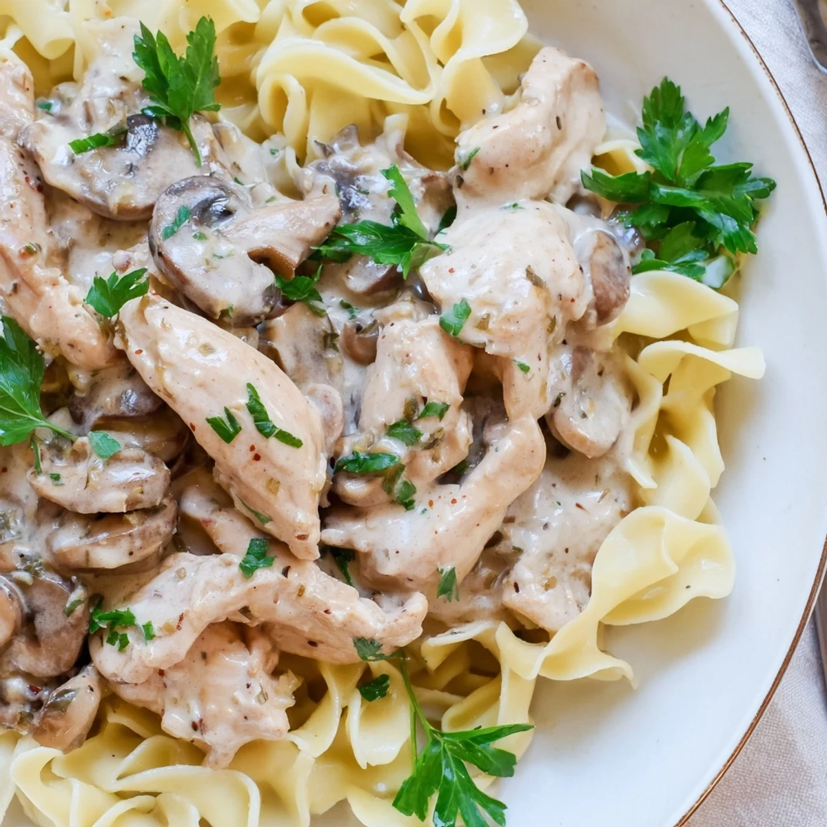 A close-up of golden Chicken and Mushroom Stroganoff, garnished with fresh parsley, ready to be served for a comforting weeknight dinner.