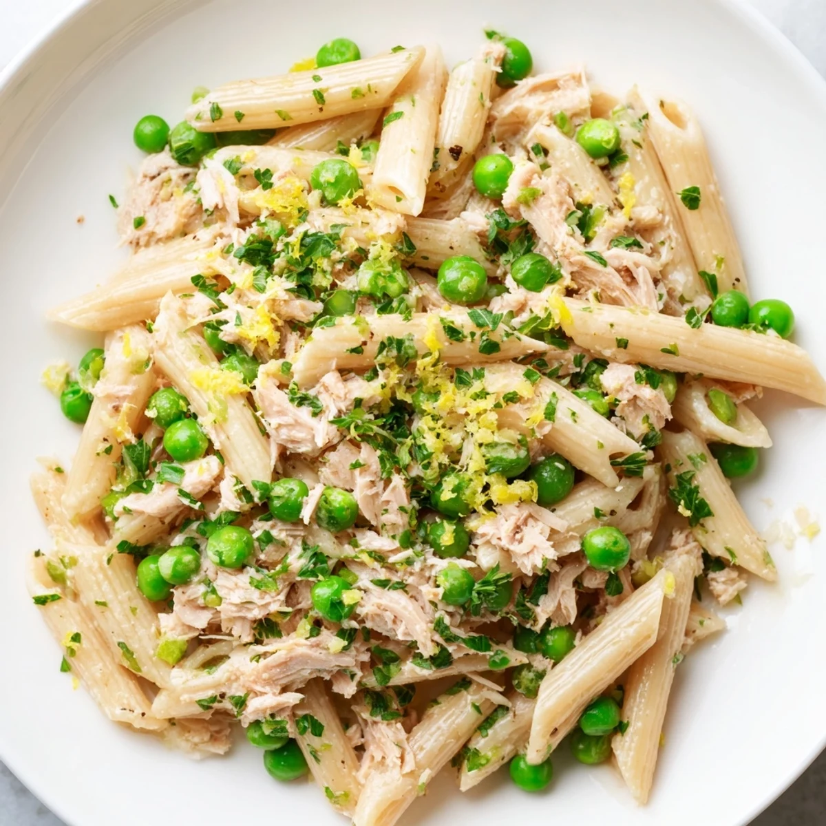 A vibrant bowl of Lemony Tuna Pasta Salad with tender fusilli, flaked tuna, sweet peas, and fresh herbs, served chilled.