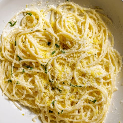 Close-up of bright Lemon Ricotta Pasta in a white bowl, topped with lemon zest and grated Parmesan.