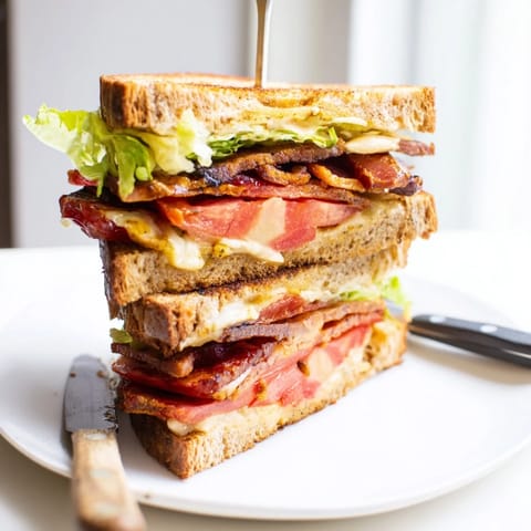Vegan Bacon BLT Grilled Cheese with crispy edges, served warm and cut in half on a rustic wooden board.