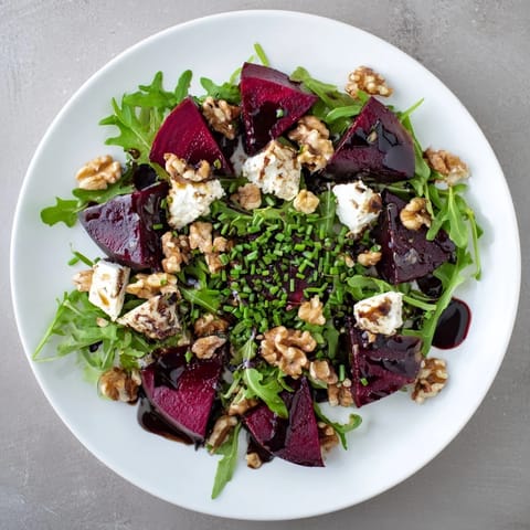 Golden roasted beet wedges and creamy crumbled goat cheese are artfully arranged over a bed of peppery baby arugula, topped with crunchy toasted walnuts in the vibrant Roasted Beet Goat Cheese Salad.