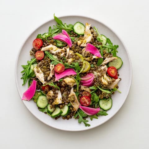 Lentil & Chicken Spring Salad topped with tangy pickled red onions and sliced cherry tomatoes, ready to eat.