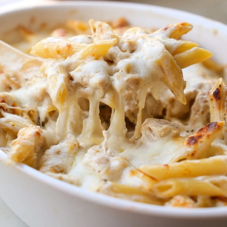 A close-up of Chicken Ranch Pasta Bake served in a white dish, garnished with fresh chives and ready to enjoy.