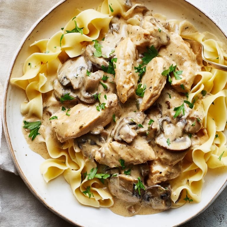 Uplifting dinner idea: savory Chicken and Mushroom Stroganoff plated over egg noodles, with steam rising from the creamy, paprika-infused sauce.