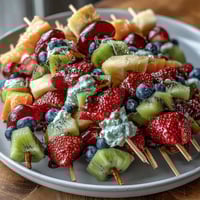 Colorful bento box with fruit skewers, yogurt dip, and kid-friendly sandwiches—perfect for school lunches or picnics.